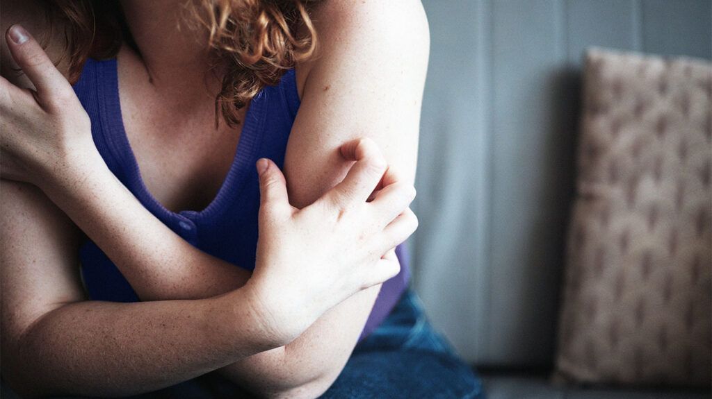 A person scratching their arm due to experiencing formication.