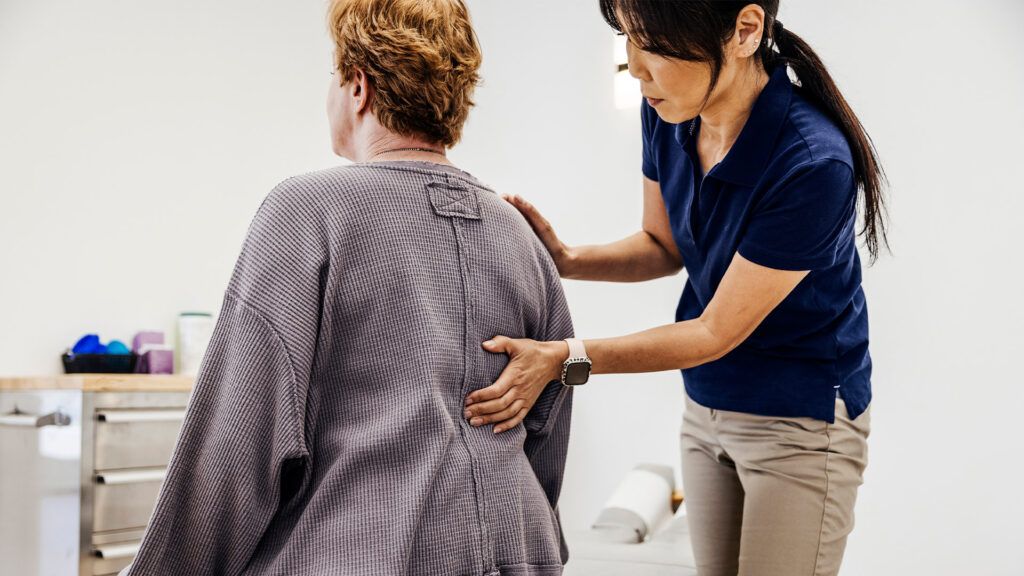 A doctor touching the back of a woman with back pain