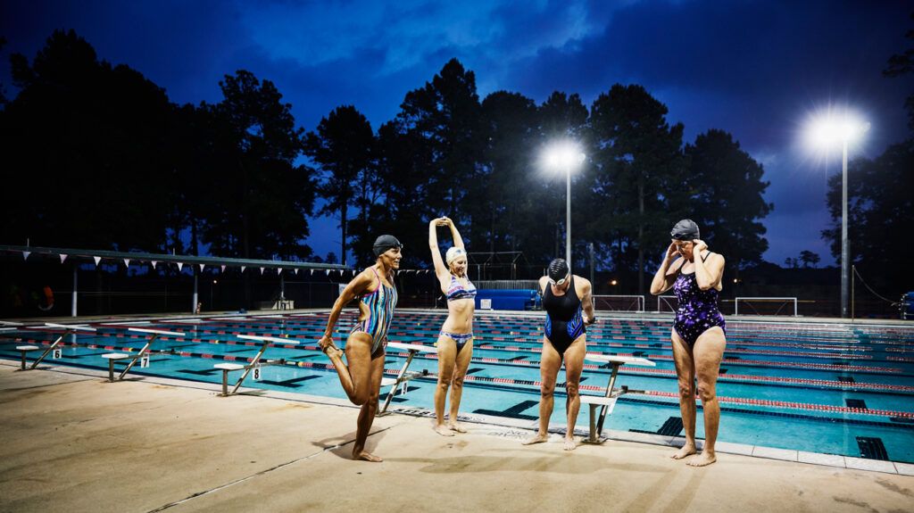 a group of swimmers by a poolside at night