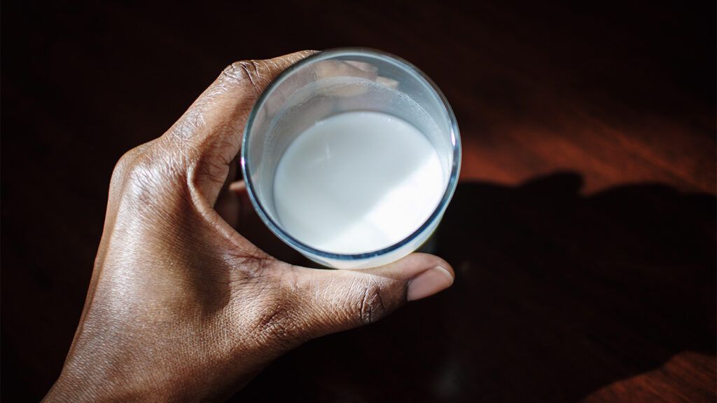 close-up of hand holding glass of milk