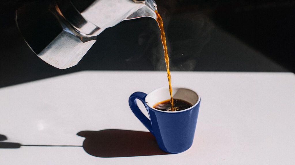 Coffee poured from a moka pot into a cup