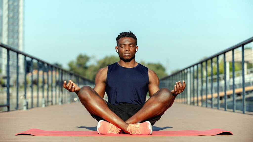 man sitting on exercise mat meditating-1