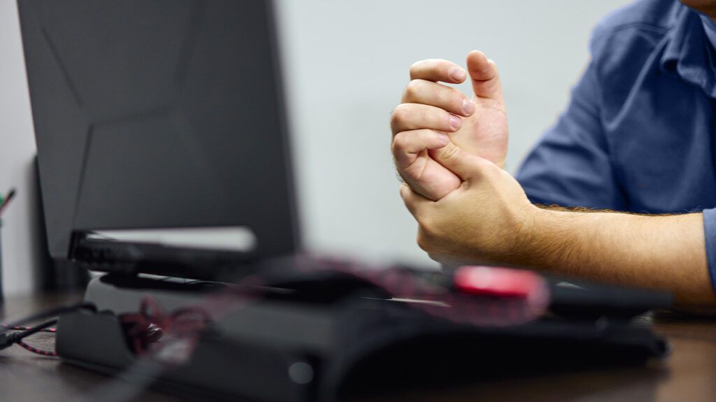 A person holding their hand and feeling their knuckles-1.