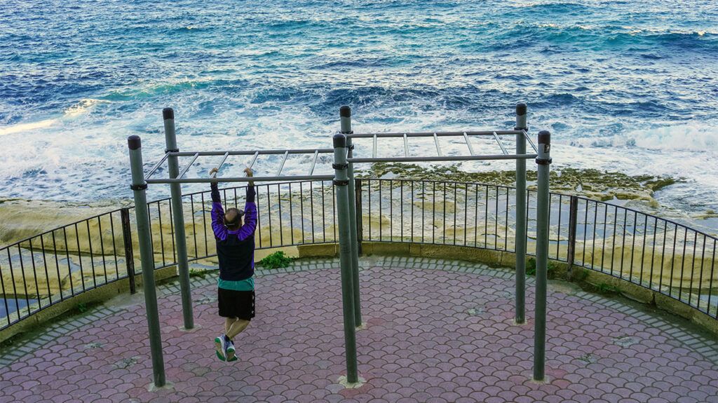 older person using strength training poles on seafront