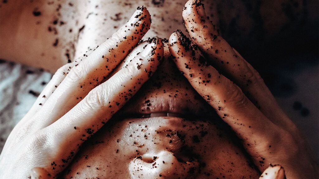 Person using exfoliating coffee scrub on the face.