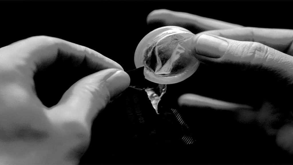 fingers opening a condom packet