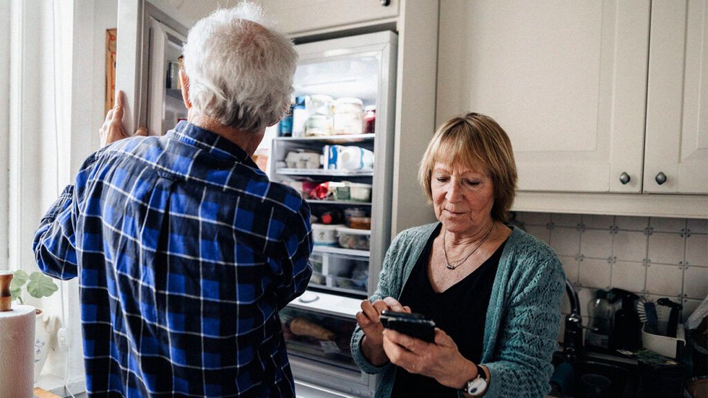 Older couple opening and looking into refrigerator.