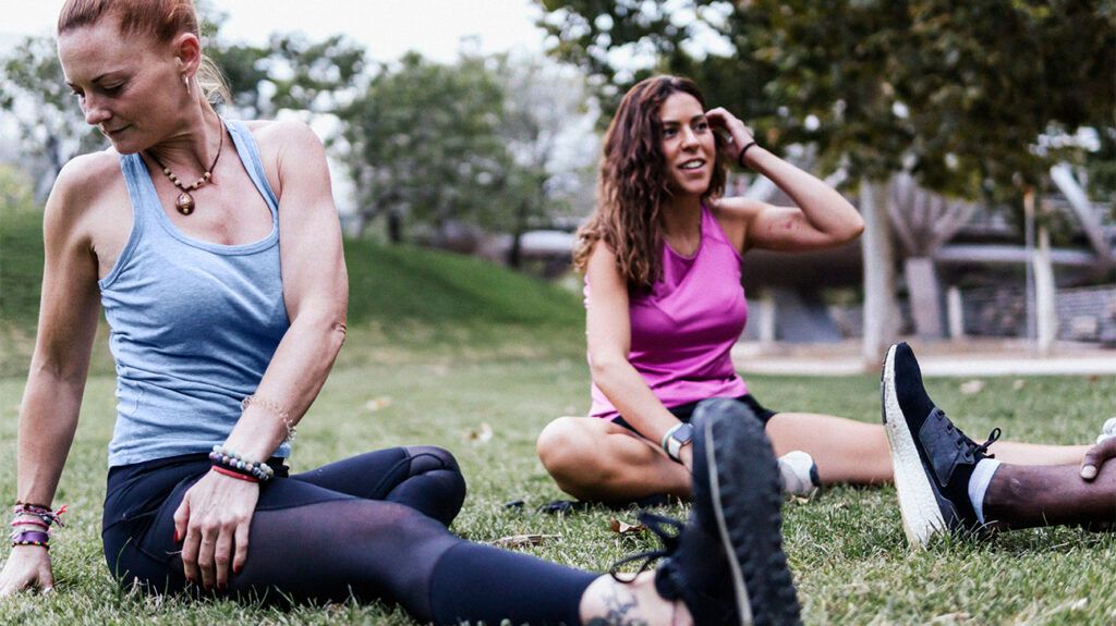 Group of friends stretching on grass in park