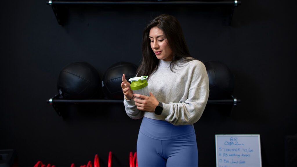 a woman drinking a creatine protein shake