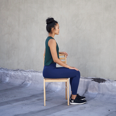 A woman sat on a chair twisting from the waist.