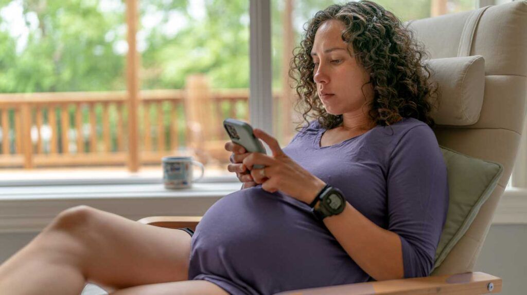A pregnant person on their phone.