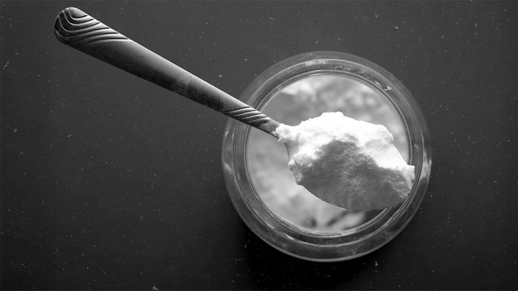 A spoon of baking soda rising from a small jar.-1