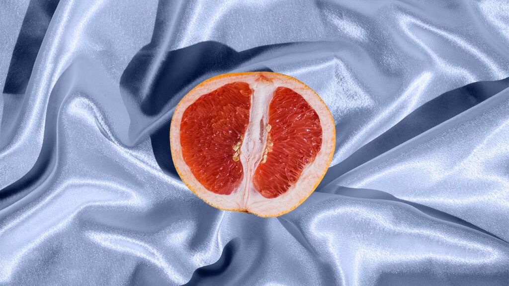 A grapefruit on a blue silk sheet.