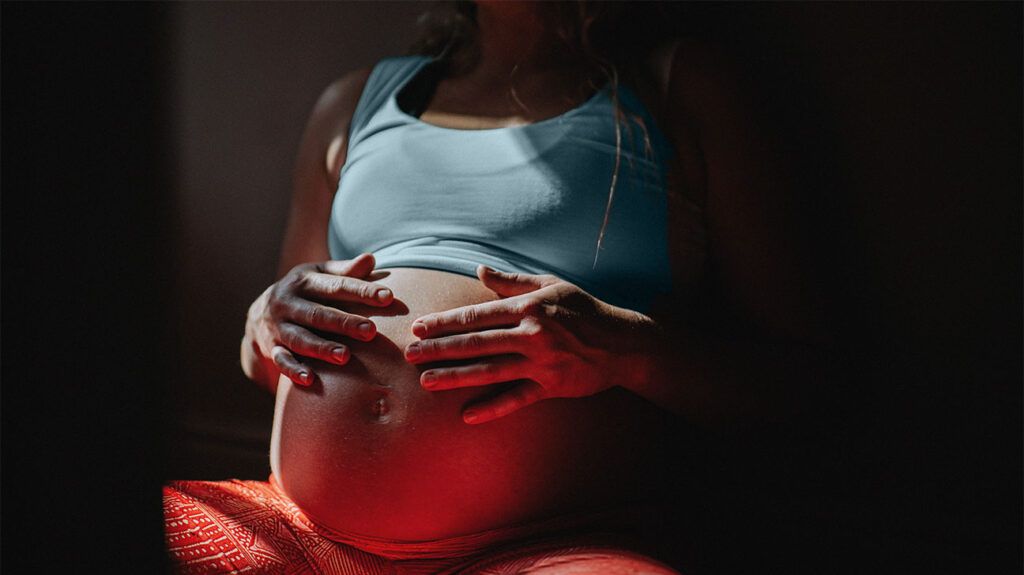 Close-up of a woman rubbing her baby bump with space for copy.