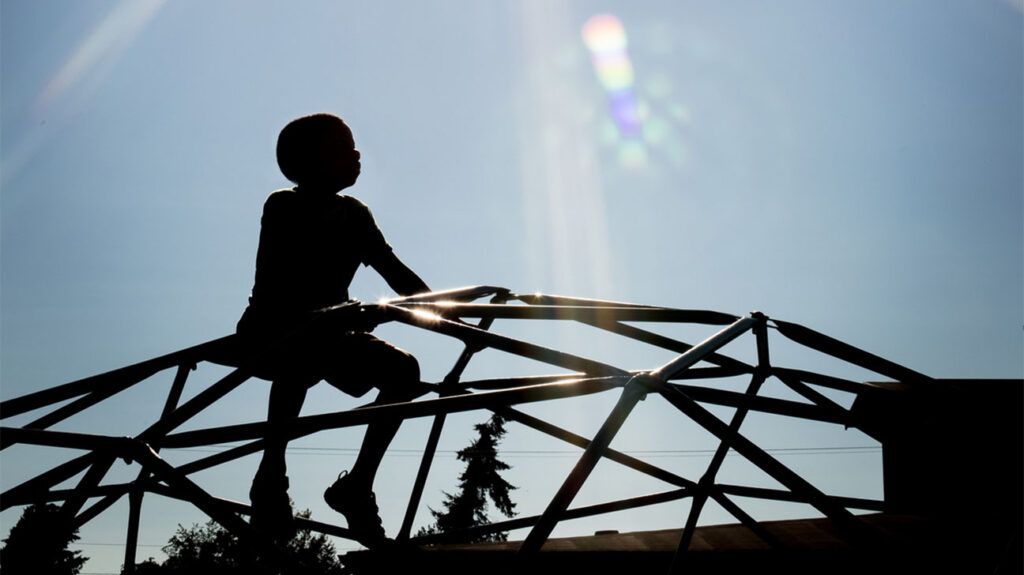 silhouette of child on playground climbing dome silhouette of child on playground climbing dome