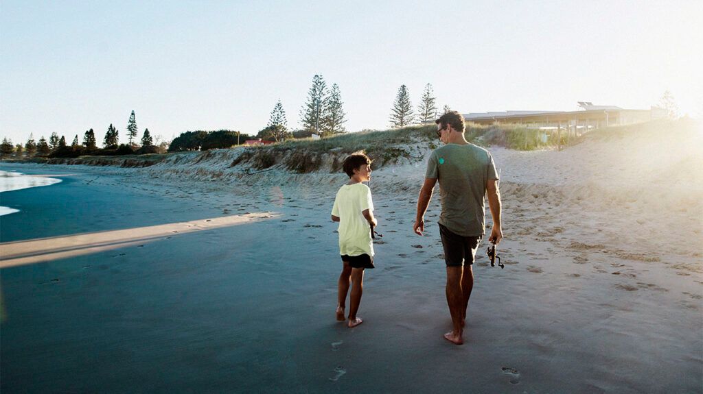 A child and a caregiver walking on a beach-2.