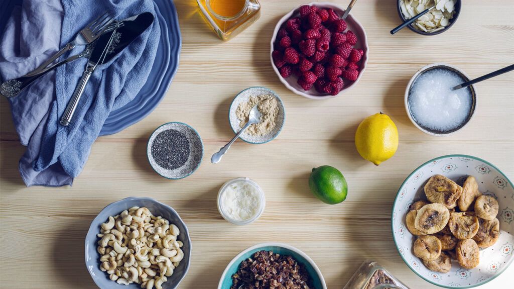 An aerial view of a breakfast spread of cashew nuts, granola, berries, and chia seeds as part of a plant-based lifestyle
