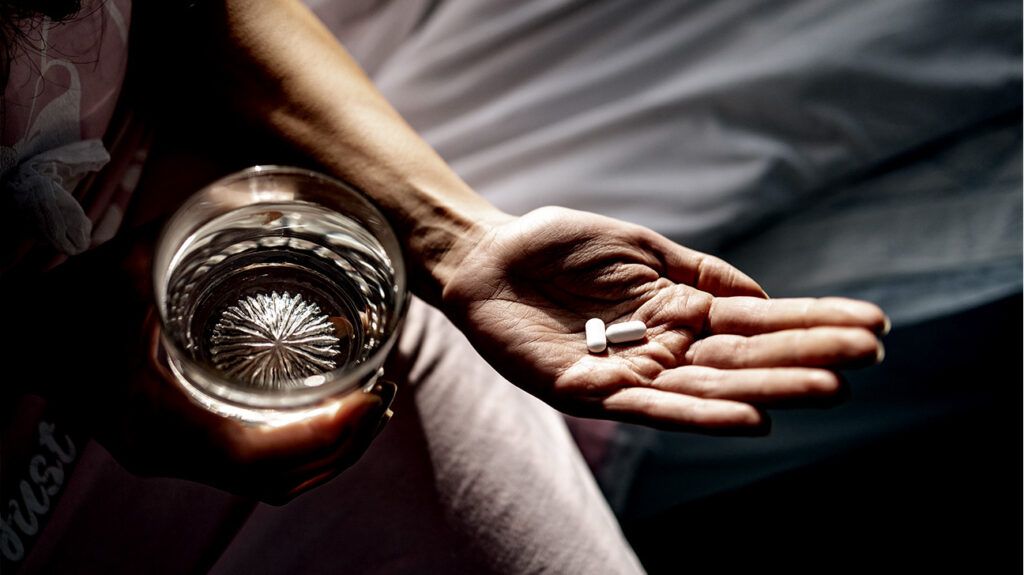 two white pills on person's outstretched palm