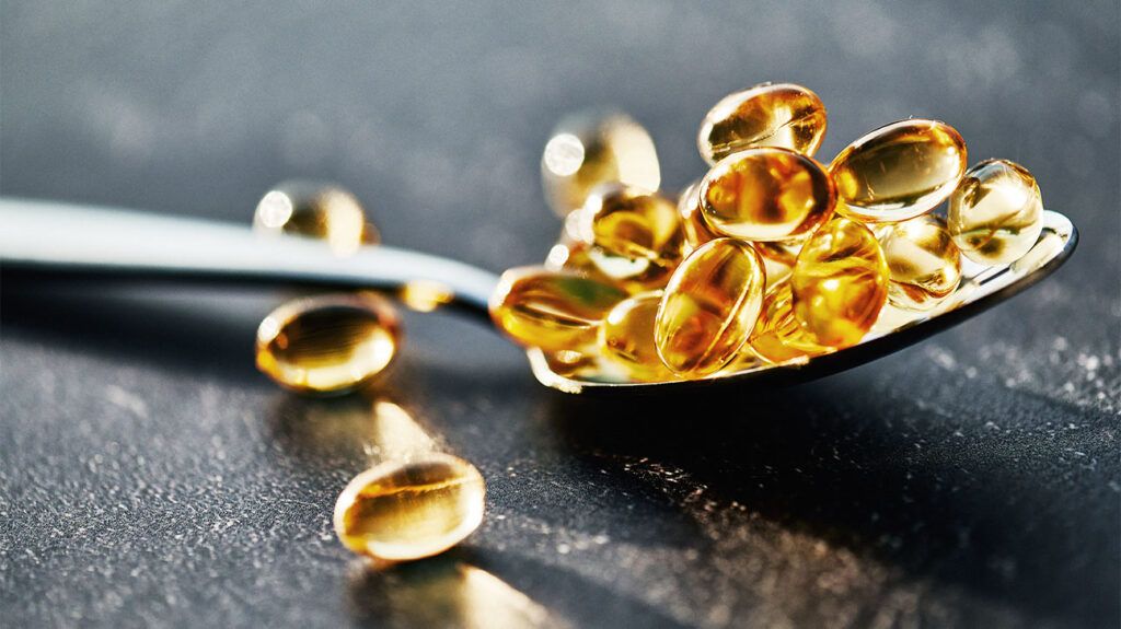 Golden Softgel Capsules on Silver Spoon