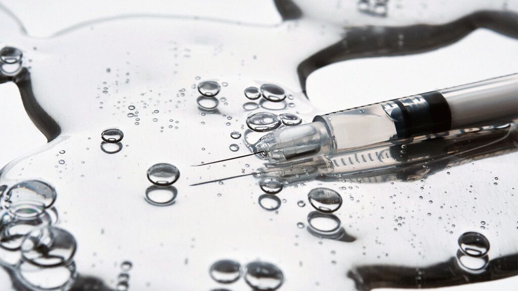 A black and white image of a syringe with droplets around it.-2