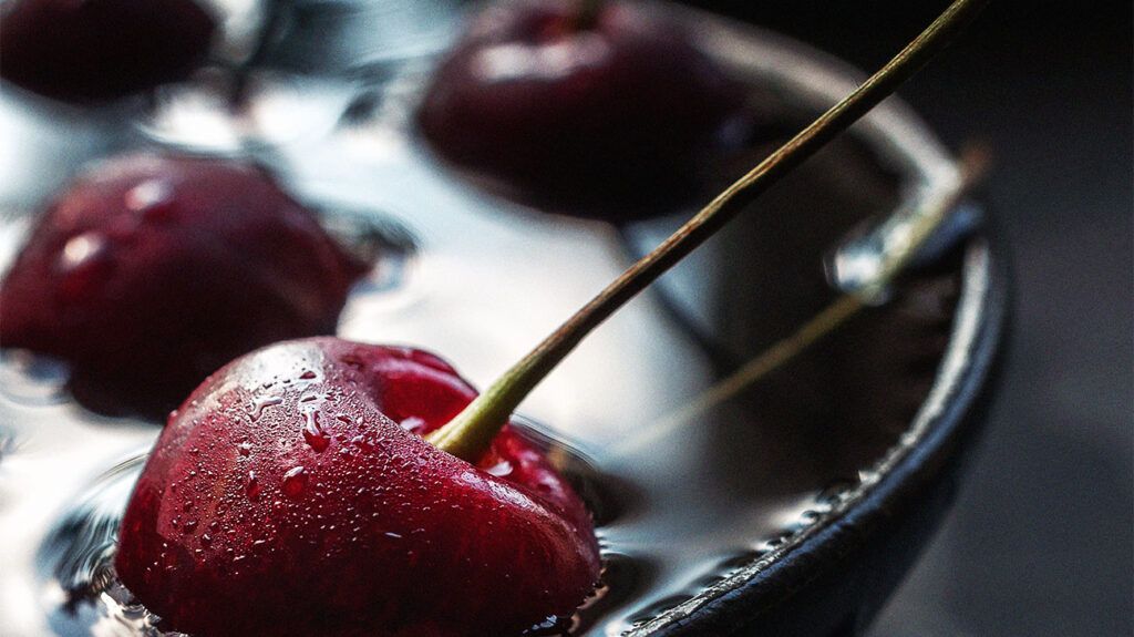 유리잔 속 주스에 담긴 체리의 클로즈업.
