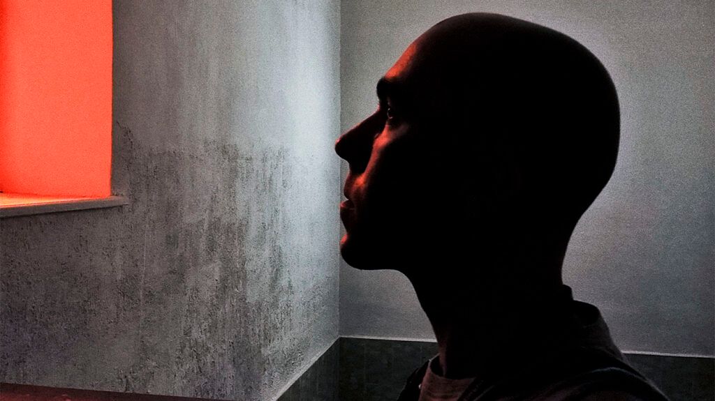 A bald person looking up in a plain room.-2