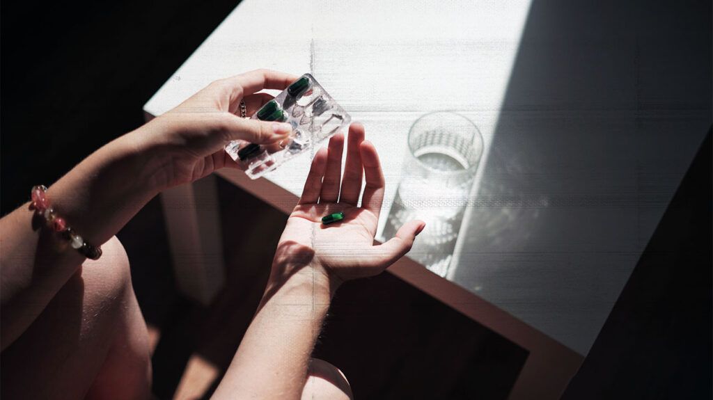 Female hands holding pills and glass of water, taking medicine in morning 