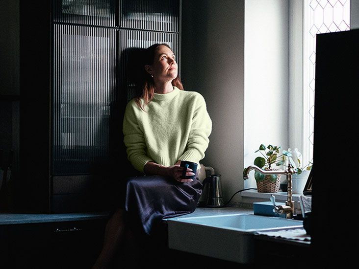 Woman daydreaming on a kitchen counter with a cup of tea