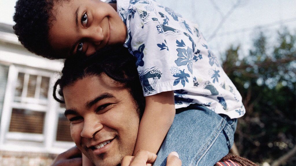 A smiling child sitting on a smiling man's shoulders. -2