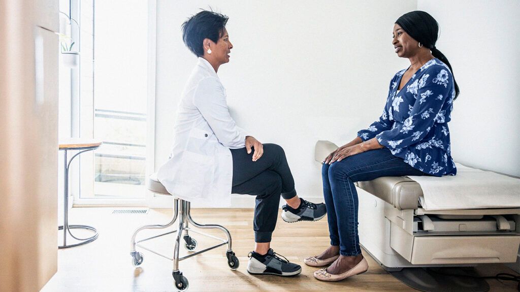 Doctor discussing treatment with woman in exam room-1