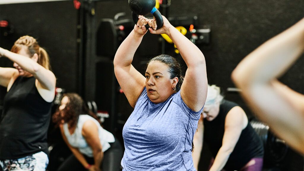 A middle-aged woman lifting weights during a workout class