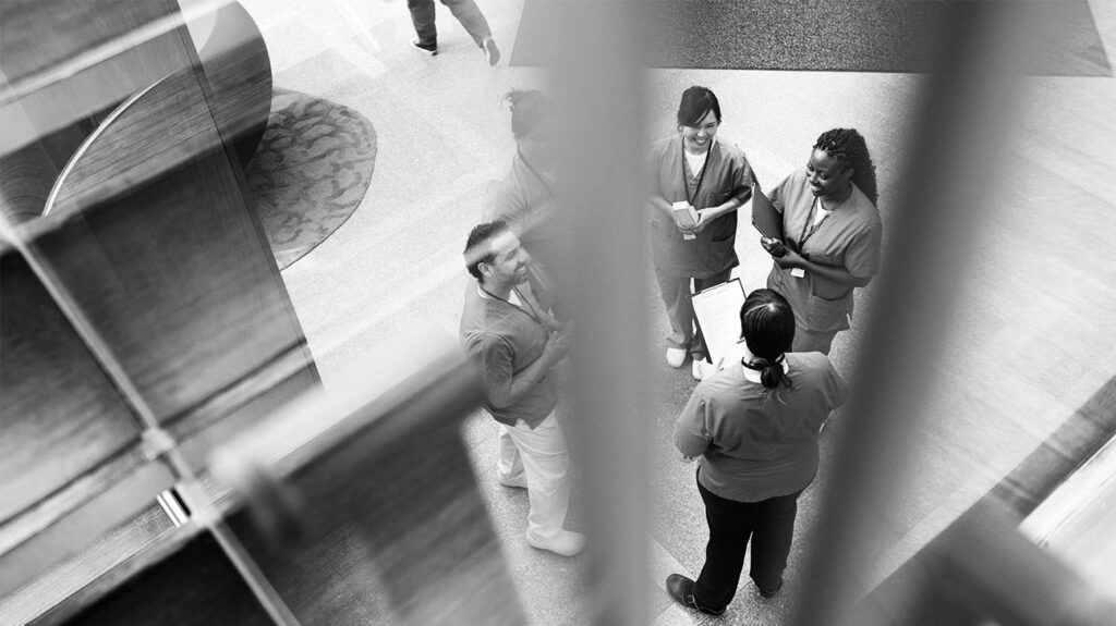 High angle view of healthcare workers talking in a hospital lobby.