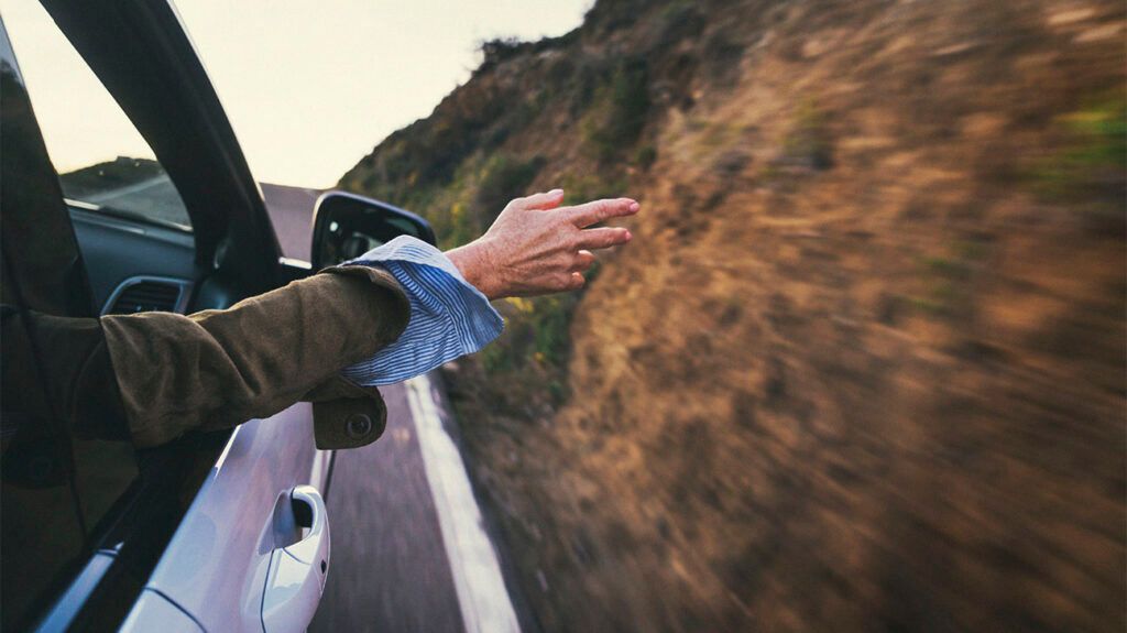 A person reaching their hand out a car window 1