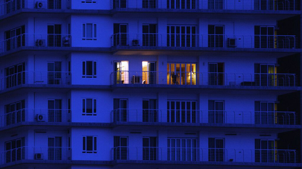 A block of apartments at night with only one that has lights on.-2
