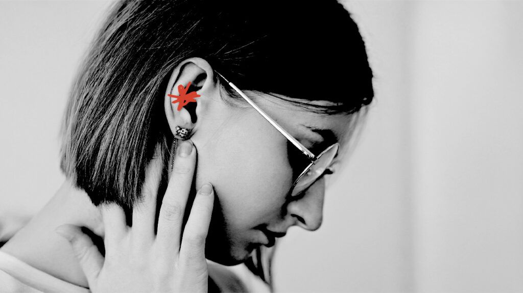 A person holding their neck, behind their ear. Ear pain is marked with a red cross
