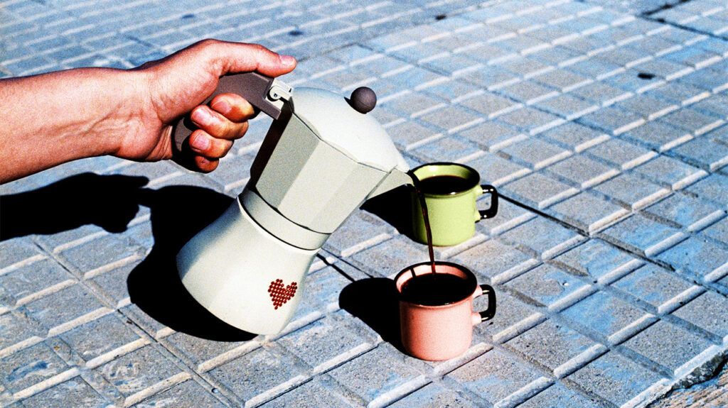 espresso coffee maker pouring coffee into pink and green tin cups