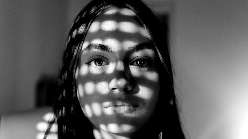 A person's face with a pattern of light across it.-1