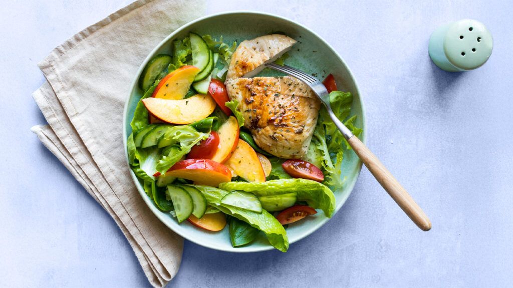 bowl of green chicken with fresh salad