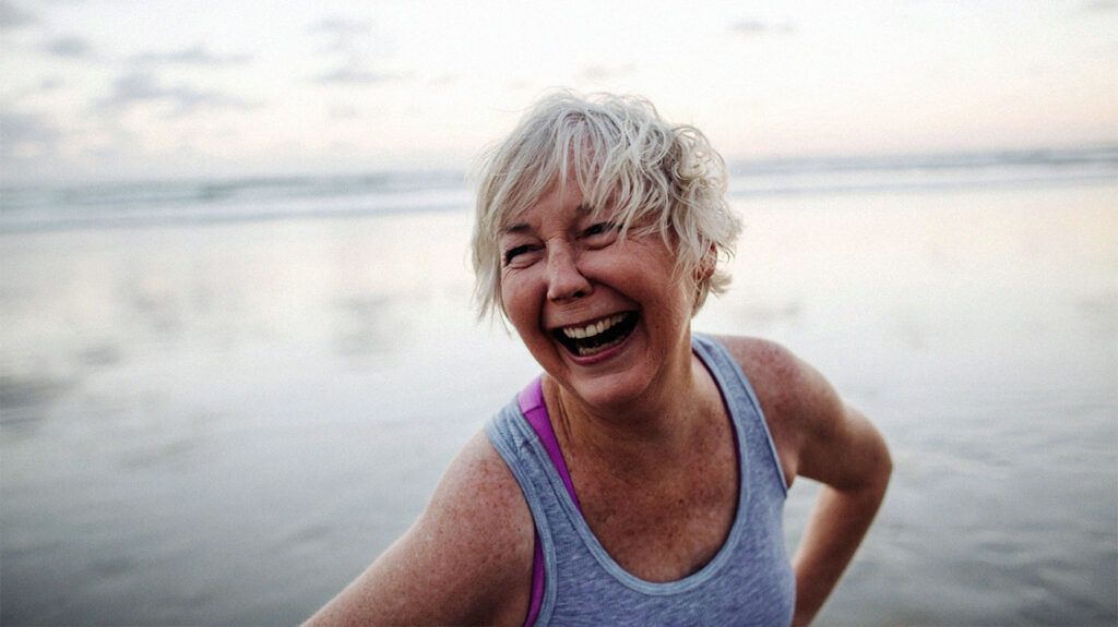 An older adult woman laughing, hands on the hips looking to the side