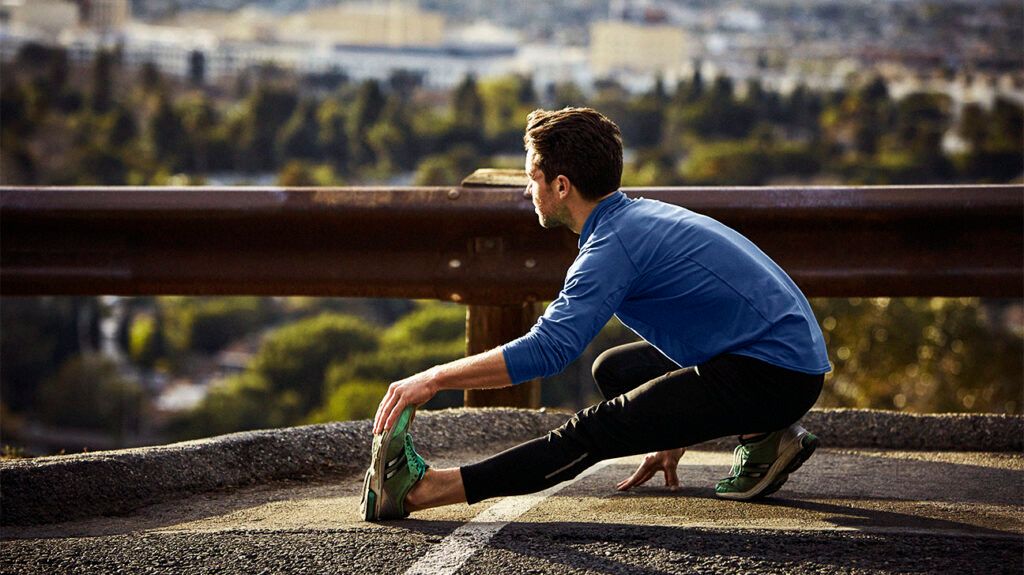 A person in running clothes stretching out their knee outside.-2