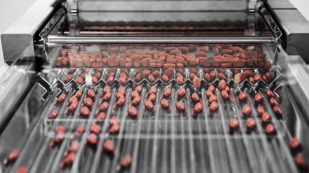 Metformin pills used to treat diabetes on a conveyor belt at a factory