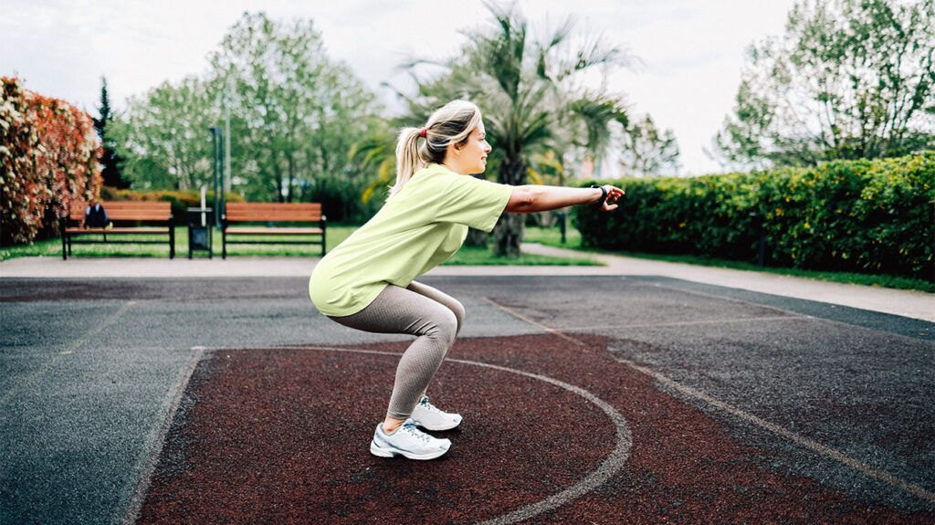Woman doing a squat outdoors with attention to hip and pelvic alignment