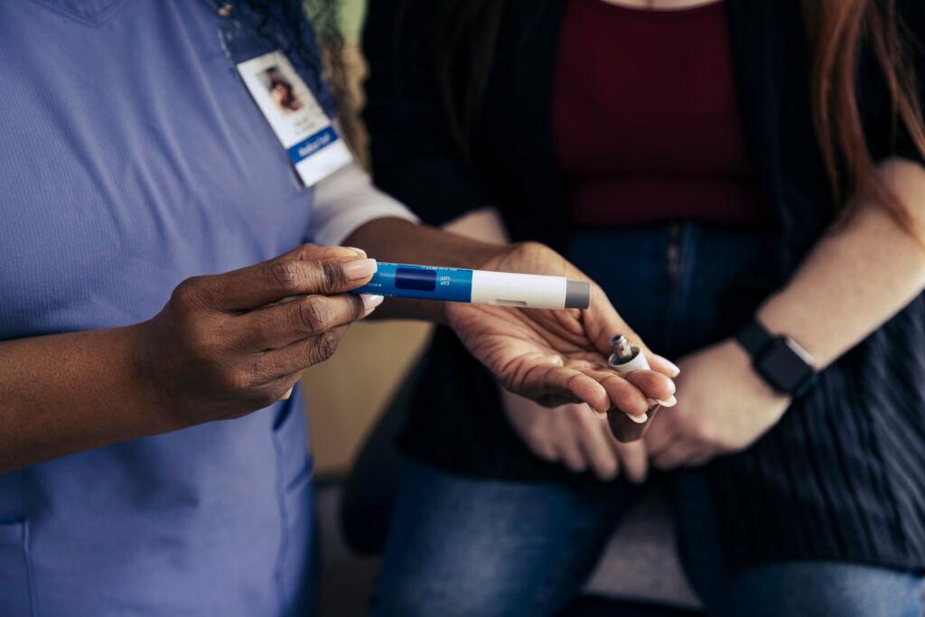 A person holding a GLP-1 weight loss injection pen in an exam room at a doctor's office