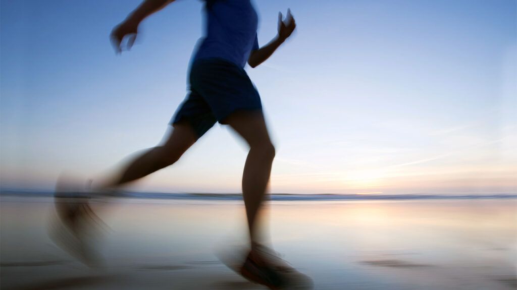 blurry image of person jogging along seafront