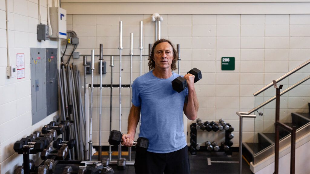 A man lifting dumbbells to do arm curls to build muscle