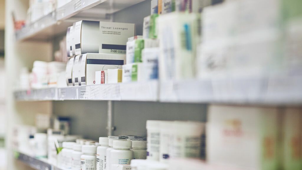 Various boxes of medications stacked on a shelf at a pharmacy