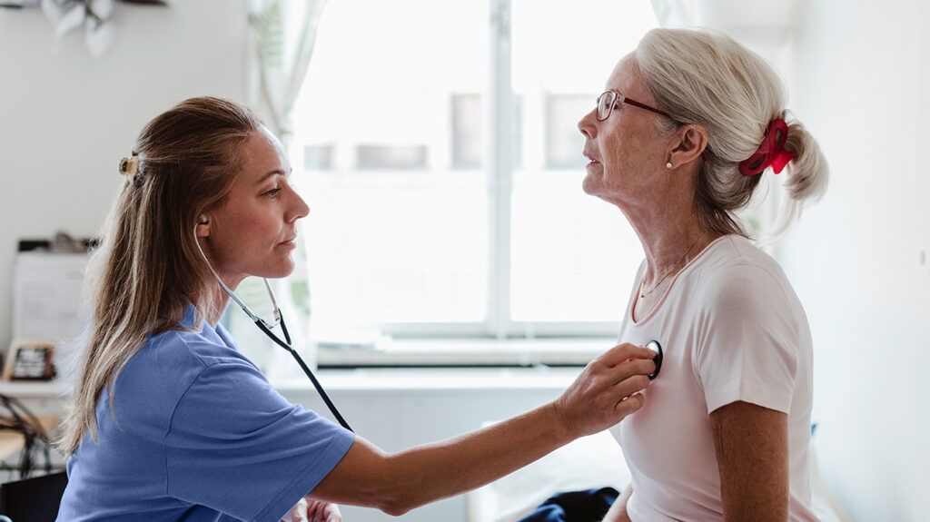 older white woman having her heart checked by younger female doctor with stethoscope