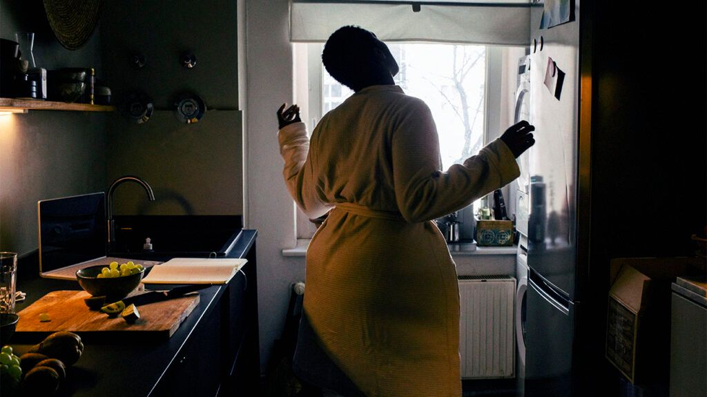 Carefree young woman wearing bathrobe dancing in kitchen at home