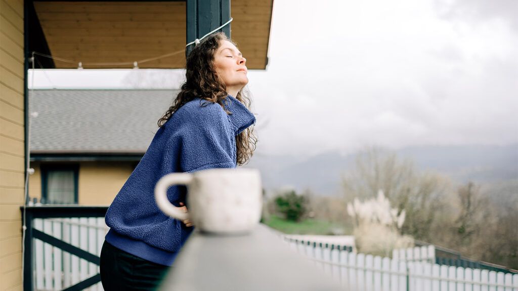 Female on a balcony with a cup of tea looking calm