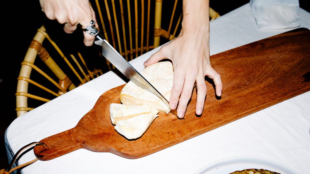person slicing slab of cheese